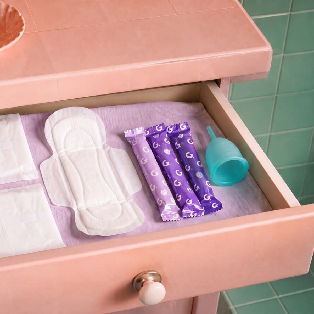 A bathroom drawer holding wrapped Garnuu tampons, pads and a cup